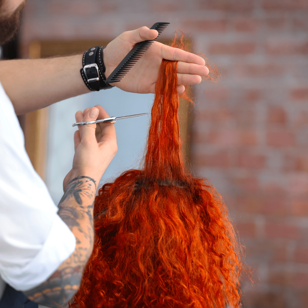 Stylist cutting curly hair with scissors close to curls