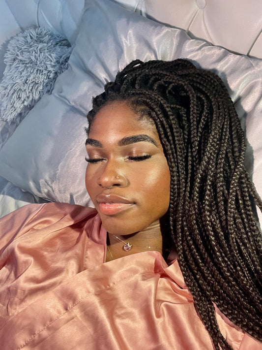 Person with braids sleeping on a satin pillowcase to protect curls from frizz and tangles.